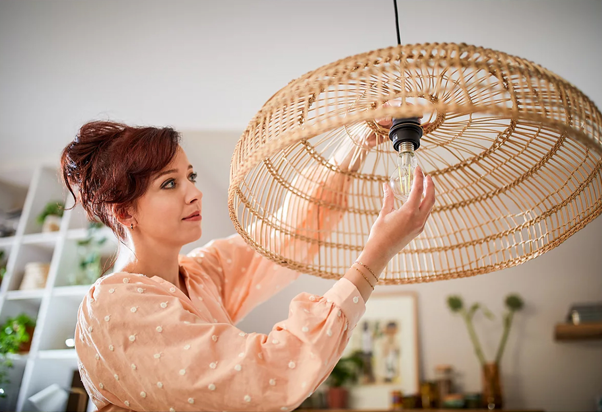 Μια γυναίκα αλλάζει τον λαμπτήρα στο φωτιστικό της με την λάμπα Philips Ultra Efficient.